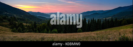 Wunderschöne Panorama der Landschaft mit Wald Fichte in den Bergen. schöne Landschaft mit rötlichen Himmel über dem Tal in der Dämmerung im frühen Herbst Stockfoto