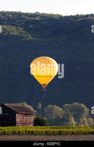 Hot Air Balloon beleuchtet durch die untergehende Sonne, Dordogne, Aquitaine, Frankreich, Europa. Stockfoto