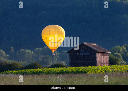 Hot Air Balloon beleuchtet durch die untergehende Sonne, Dordogne, Aquitaine, Frankreich, Europa. Stockfoto