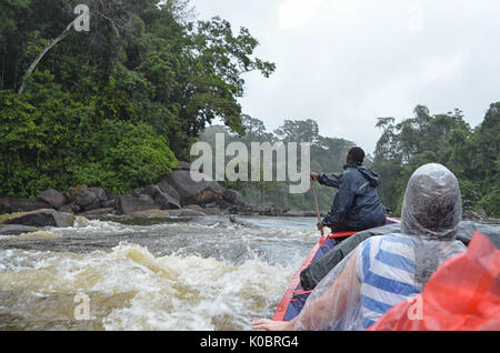 Menschen in einem kleinen Boot im Regen auf einen wilden Fluss Stockfoto