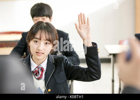 Portrait der Schule Mädchen ihre Hand und andere Schüler in der Klasse Stockfoto