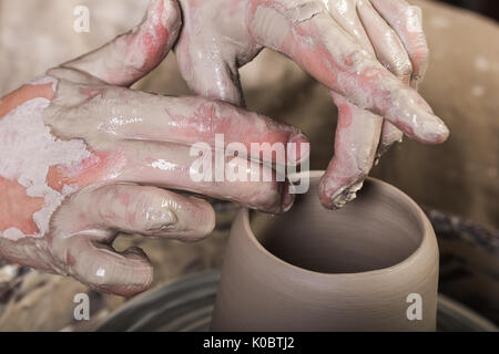 Keramik, Werkstatt, Keramik Kunst Konzept - männliche Hände sculpt einige Neue utensil mit Fingern und Wasser, Mann die Hände arbeitet mit Töpferscheibe und Rohstoff Ton, die Ansicht zu schließen. Stockfoto