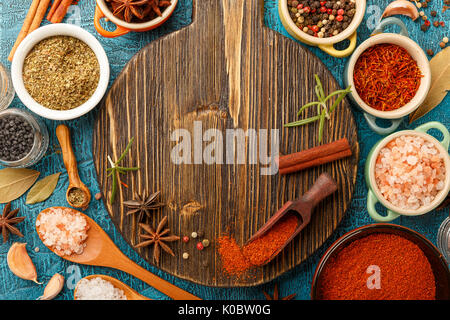 Trockene bunte Gewürze und Würzen Anis, Paprika, Safran, Pfeffer, Salz, Lorbeerblatt, Zimt in kleinen Schüsseln auf blauem Hintergrund. Ansicht von oben Stockfoto