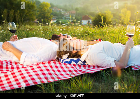 Paar liegend auf einer Picknickdecke holding Glas Wein Stockfoto