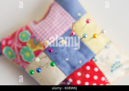 Close-up auf nähen Werkzeuge, Patchwork, Schneiderei und Fashion Concept - Makro top Blick auf bunte gestickte Kissen mit vielen schönen Pins, selektiver Fokus, flach. Stockfoto