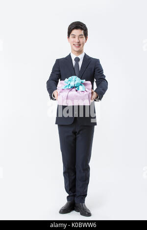 Junge lächelnde Geschäftsmann Holding ein Geschenk Box Stockfoto