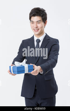 Junge lächelnde Geschäftsmann Holding ein Geschenk Box Stockfoto