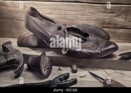 Alte Schuhe und Reparatur Werkzeuge auf dem hölzernen Tisch, Nahaufnahme Stockfoto