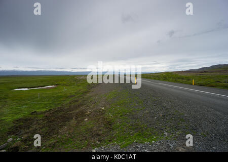 Island - Highway durch grüne Landschaft vor der weißen Berge Stockfoto