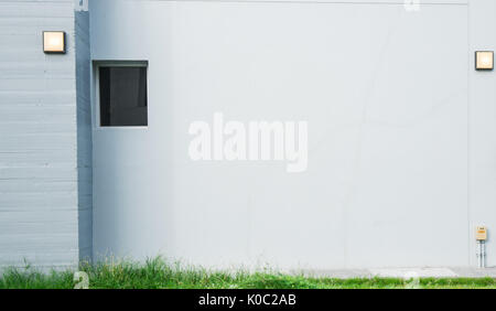 Graue Betonwand mit Lampe und haben grünes Gras an der Unterseite Stockfoto