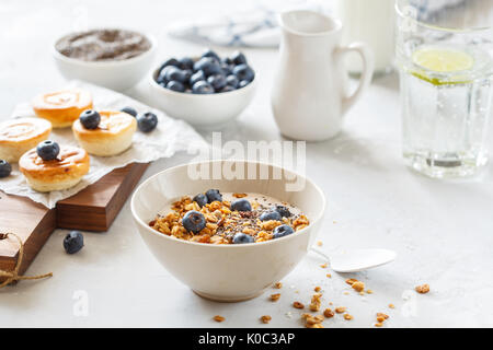 Müsli mit Joghurt und mini Käsekuchen mit Heidelbeeren zum Frühstück. Stockfoto