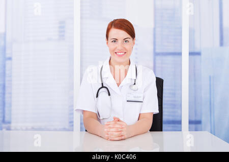 Porträt von schöne junge Ärztin am Schreibtisch in Klinik Stockfoto
