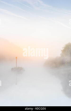 Die Sonne beginnt ein warmes Orange glühen durch den Nebel auf dem Fluss Severn bei Norton in Gloucestershire in der Morgendämmerung in Mitte August zu werfen. Stockfoto