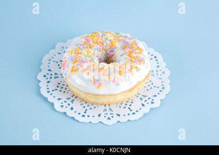Eine mehrfarbige Donuts auf einem deckchen Papier und einem bunten Hintergrund dargestellt. Stockfoto