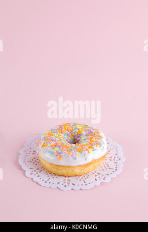 Eine mehrfarbige Donuts auf einem deckchen Papier und einem bunten Hintergrund dargestellt. Stockfoto