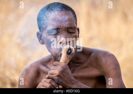 Saan Mann rauchen in der buschmann Jäger Lebendige Geschichte Dorf. Grashoek, Otjozondjupa, Namibia, Afrika. Stockfoto