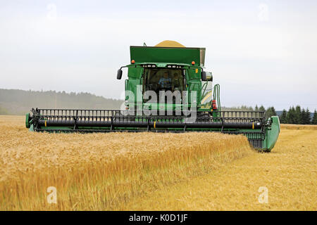 SALO, Finnland - 18. AUGUST 2017: John Deere Mähdrescher T660 mit Schneidwerk 630D ernten Gerste, den Korntank fast voll, auf Puontin Peltopaivat Ag Stockfoto