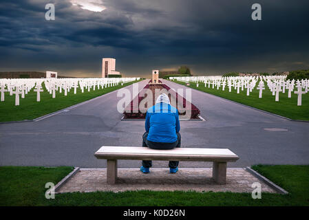 Mann sitzt auf einer Bank, und denken Sie dabei an alle Soldaten, die durch dieses American Memorial Cemetery geehrt, in Luxemburg. Stockfoto