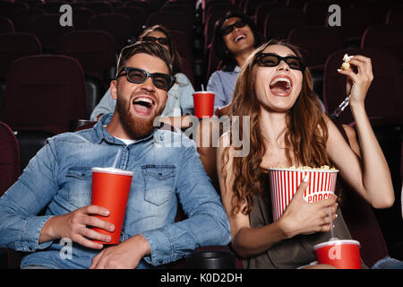 Bild von Lachen Freunde im Kino ansehen Film sitzen Popcorn essen und trinken Perlwein mit Süßwasser. Stockfoto