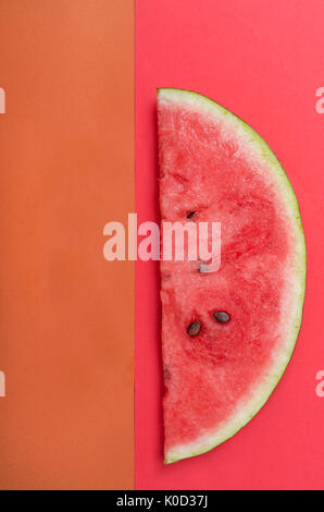 Scheibe Wassermelone mit Steinen auf rotem Hintergrund Stockfoto