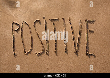 High-Angle Shot des Wortes positiv in den Sand des Strandes geschrieben Stockfoto