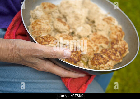 Weibliche Hände, die Pfanne mit bereit, Schnitzel zu essen, Nahaufnahme, geringe Tiefenschärfe Stockfoto
