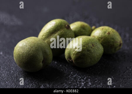 Frische grüne Walnüsse in die Haut direkt vom Baum. Walnüsse auf schwarzem Hintergrund. Makro. Frische Ernte. Stockfoto