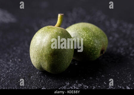 Frische grüne Walnüsse in die Haut direkt vom Baum. Walnüsse auf schwarzem Hintergrund. Makro. Frische Ernte. Stockfoto