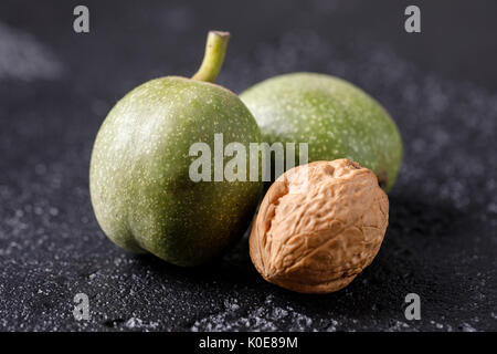 Frische grüne Walnüsse in die Haut direkt vom Baum. Walnüsse auf schwarzem Hintergrund. Makro. Frische Ernte. Stockfoto