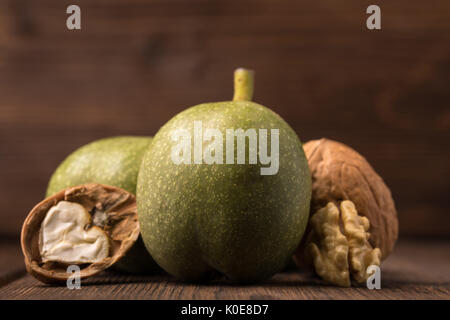 Fresh Harvest Walnüsse auf einem hölzernen Hintergrund. Grün und Braun Muttern. Shell und Schalen von Walnüssen. Walnüsse auf einer hölzernen Oberfläche Stockfoto