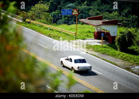 Kubanischer Oldtimer vorbei an einer Bushaltestelle an Bacunayagua Brücke Dienstleistungen, Kuba in der Nähe von Matanzas, Cuba, Stockfoto