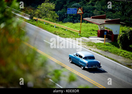 Kubanischer Oldtimer vorbei an einer Bushaltestelle an Bacunayagua Brücke Dienstleistungen, Kuba in der Nähe von Matanzas, Cuba, Stockfoto