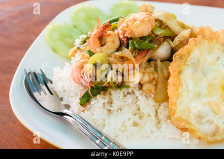 Reis mit Spiegelei mit gebratenen Garnelen und Tintenfisch Basilikum, Thai lokalen Essen. Stockfoto