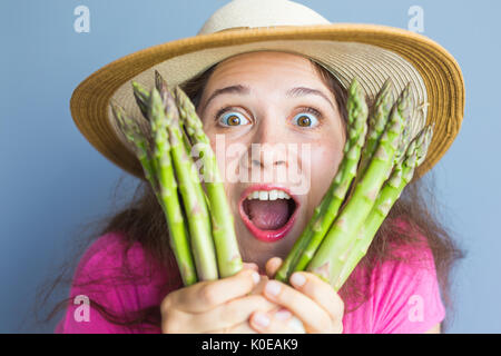 Close-up Portrait lustig überrascht Frau ist Spargel vor ihr Gesicht halten. Stockfoto