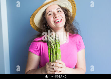 Close-up Portrait lustig überrascht Frau ist Spargel vor ihr Gesicht halten. Stockfoto