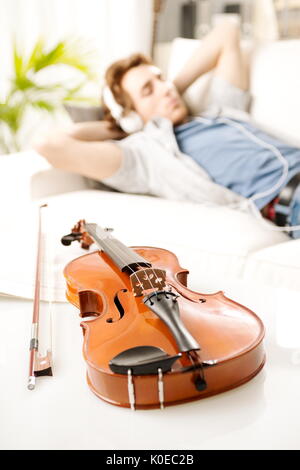 Violine-Nahaufnahme mit Mann, entspannend und anhören von Musik im Hintergrund. Stockfoto