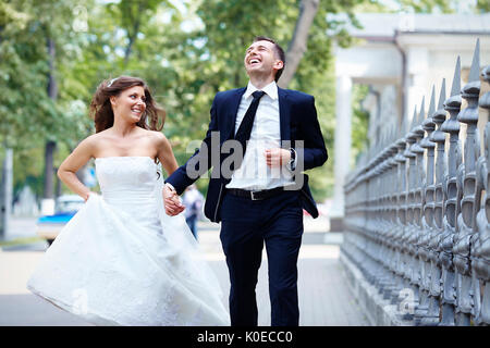 Glückliche Braut und Bräutigam laufen Lachen am Hochzeitstag Stockfoto