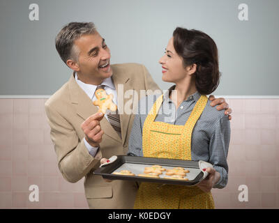 Vintage Frau hausgemachter Portion Lebkuchenmänner Cookies an ihren lächelnden Mann Stockfoto