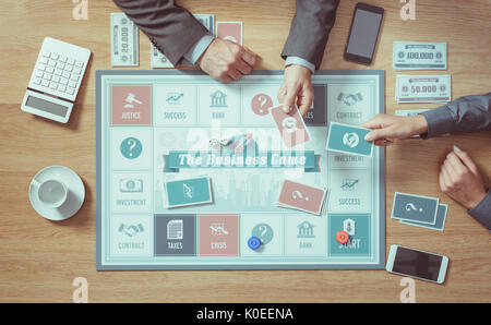 Menschen spielen eine Business Board Game, das auf einem hölzernen Tisch, Hände, die Karten, Nahaufnahme, Ansicht von oben Stockfoto