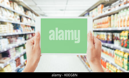 Frau mit einem digitalen Tablet im Supermarkt Gang: Shopping, Technik und augmented reality Konzept Stockfoto