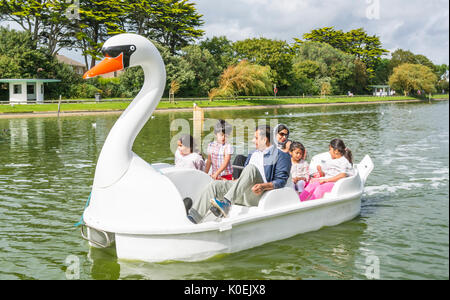 Indische Familie in einem pedelo Tretboot auf dem See an einem bewölkten Sommer in Mewsbrook Park, Littlehampton, West Sussex, England, UK. Stockfoto