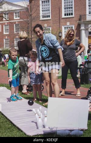 Ein Junge Schüsseln mit duckpins als junges Mädchen, Studentin und Mutter sehen, während der Spring Fair, einer studentischen Spring Carnival an der Johns Hopkins University, Baltimore, Maryland, April, 2014. Mit freundlicher Genehmigung von Eric Chen. Stockfoto