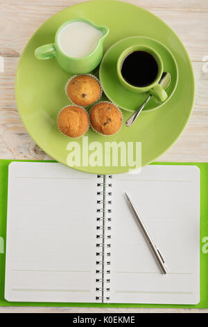 Kaffee mit Milch, Muffins und Notizblock auf hölzernen Hintergrund. Selektiven Fokus. Stockfoto