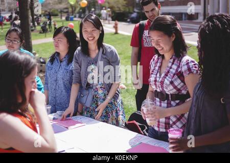 Weibliche Studierende an der Johns Hopkins University glücklich mit einer Frau, die einen Stand auf Keyser Quad an der Spring Fair, einer studentischen Spring Carnival, an einem sonnigen Tag an der Johns Hopkins University, Baltimore, Maryland, April, 2015. Mit freundlicher Genehmigung von Eric Chen. Stockfoto