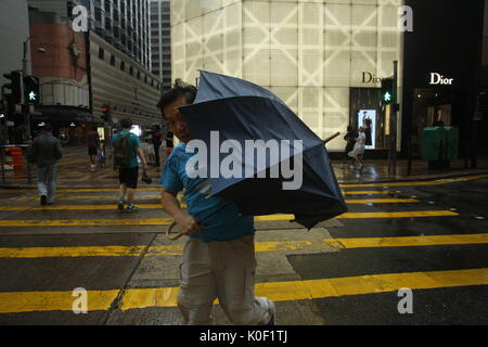 Hong Kong, Hong Kong SAR, China. 23 Aug, 2017. Ein Zebra am Shopping Center mit der gebrochenen Regenschirm während Taifun. Nr. 10 schwerer Taifun HATO Hit das Gebiet am frühen Morgen bringt schwere Dusche und starke Windböen Windgeschwindigkeit von 175 km/h in der Mitte. Credit: ZUMA Press, Inc./Alamy leben Nachrichten Stockfoto