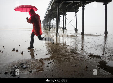 Mann verfangen in Sintflutartige Regenschauer im Sommer in der Nähe der viktorianischen Saltburn Pier. Saltburn am Meer, North Yorkshire, England, UK. Stockfoto