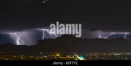 Hinter der Silhouette der Superstition Mountains blitzten häufig Blitze auf, während sich ein Gewitter in der späten Nacht durch Mesa, Arizona, zieht Stockfoto