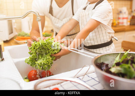 Vater mit kleinen Sohn wäscht Gemüse in der Küche vor dem Essen Stockfoto