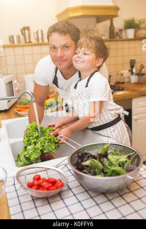 Vater mit kleinen Sohn wäscht Gemüse in der Küche vor dem Essen Stockfoto