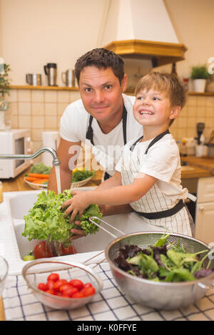 Vater mit kleinen Sohn wäscht Gemüse in der Küche vor dem Essen Stockfoto